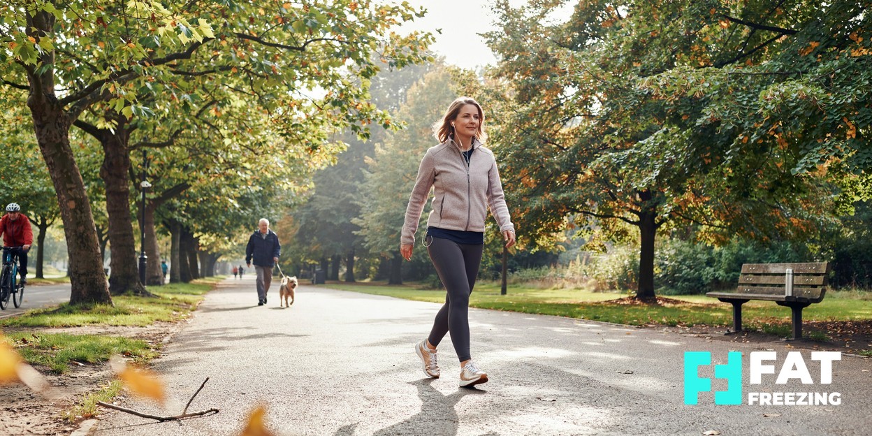 An adult walking along a tree-lined park path.